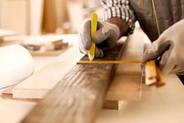 Carpenter measuring and marking lumber for a cut