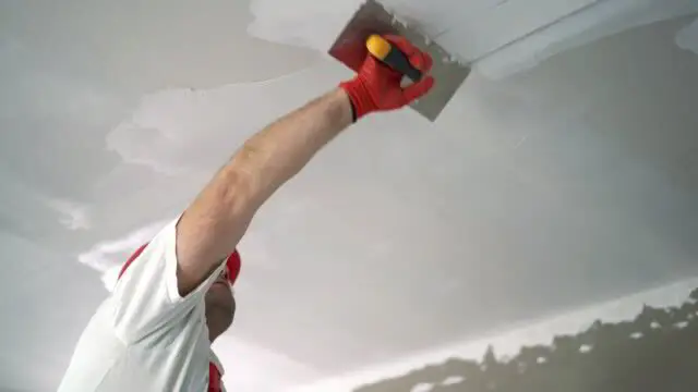 Drywall finisher applying joint compound to a ceiling seam